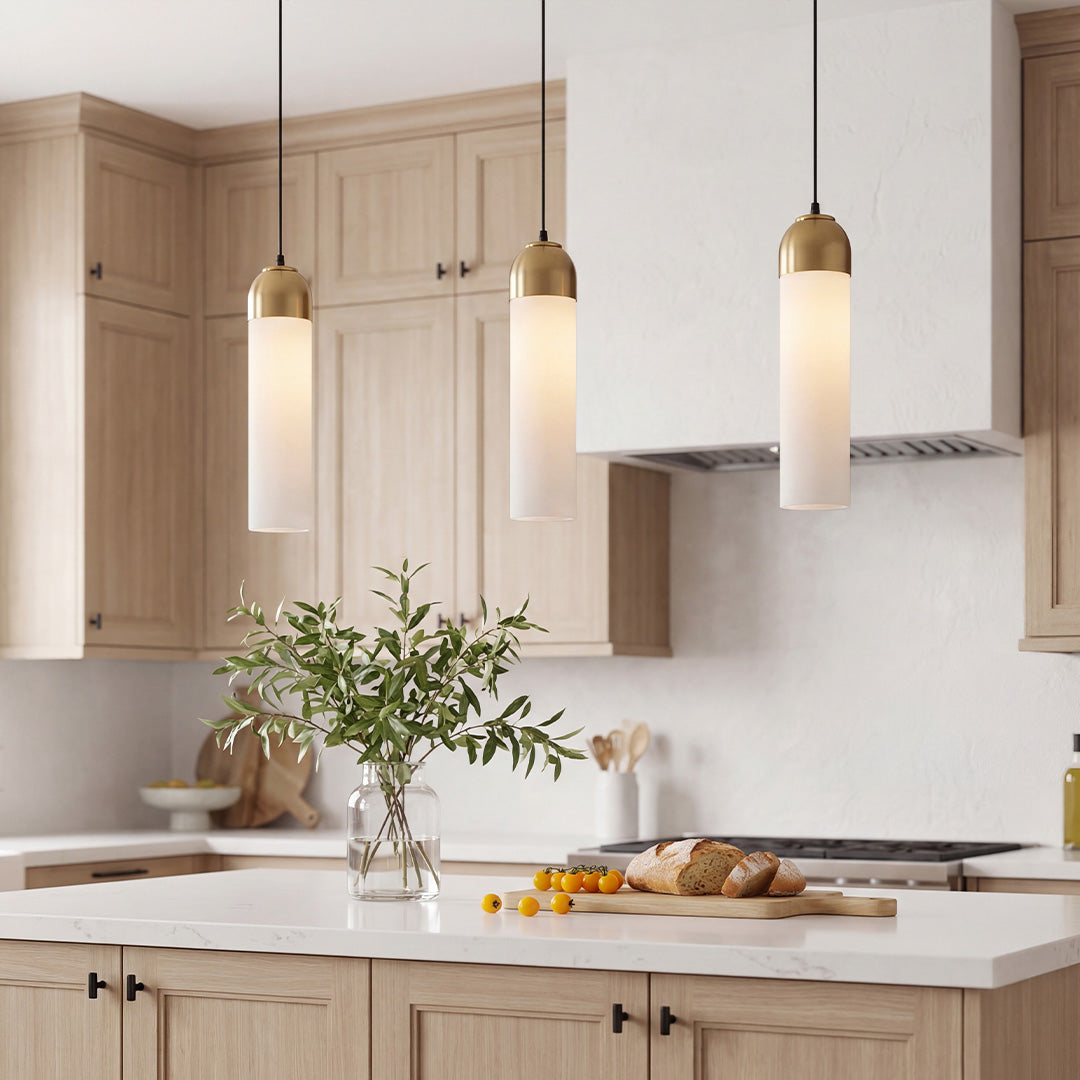 Trio of chic Gold Frosted Cylinder Pendant lights over a luxury white marble kitchen island.