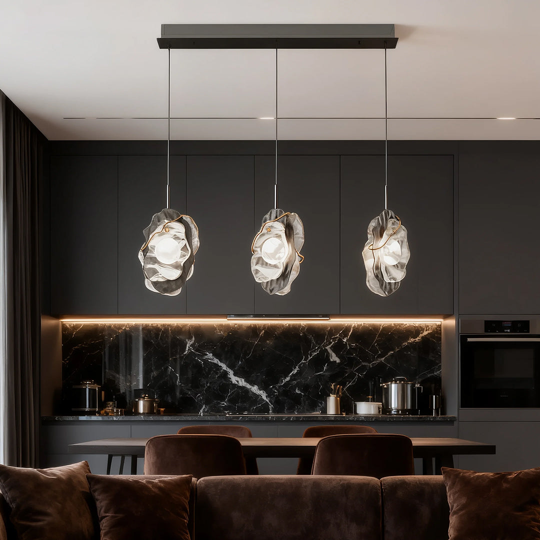 Triple fun pendant lights brightening luxury kitchen with black marble island and gold accents