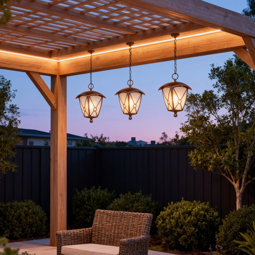 Triple outdoor LED pendant lights illuminating wooden pergola over outdoor seating at evening