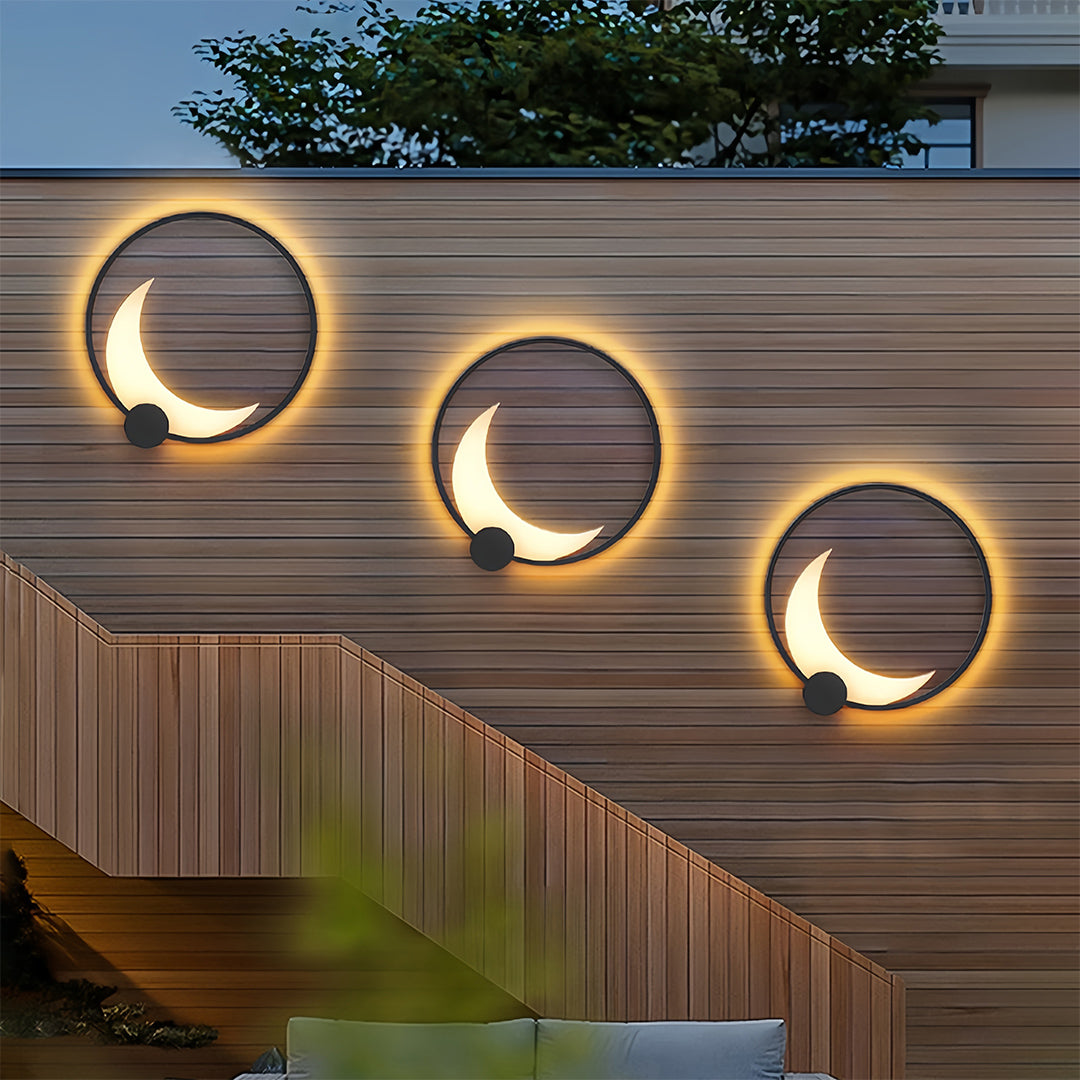 Three decorative outdoor wall lights arranged on wooden fence creating artistic illuminated display