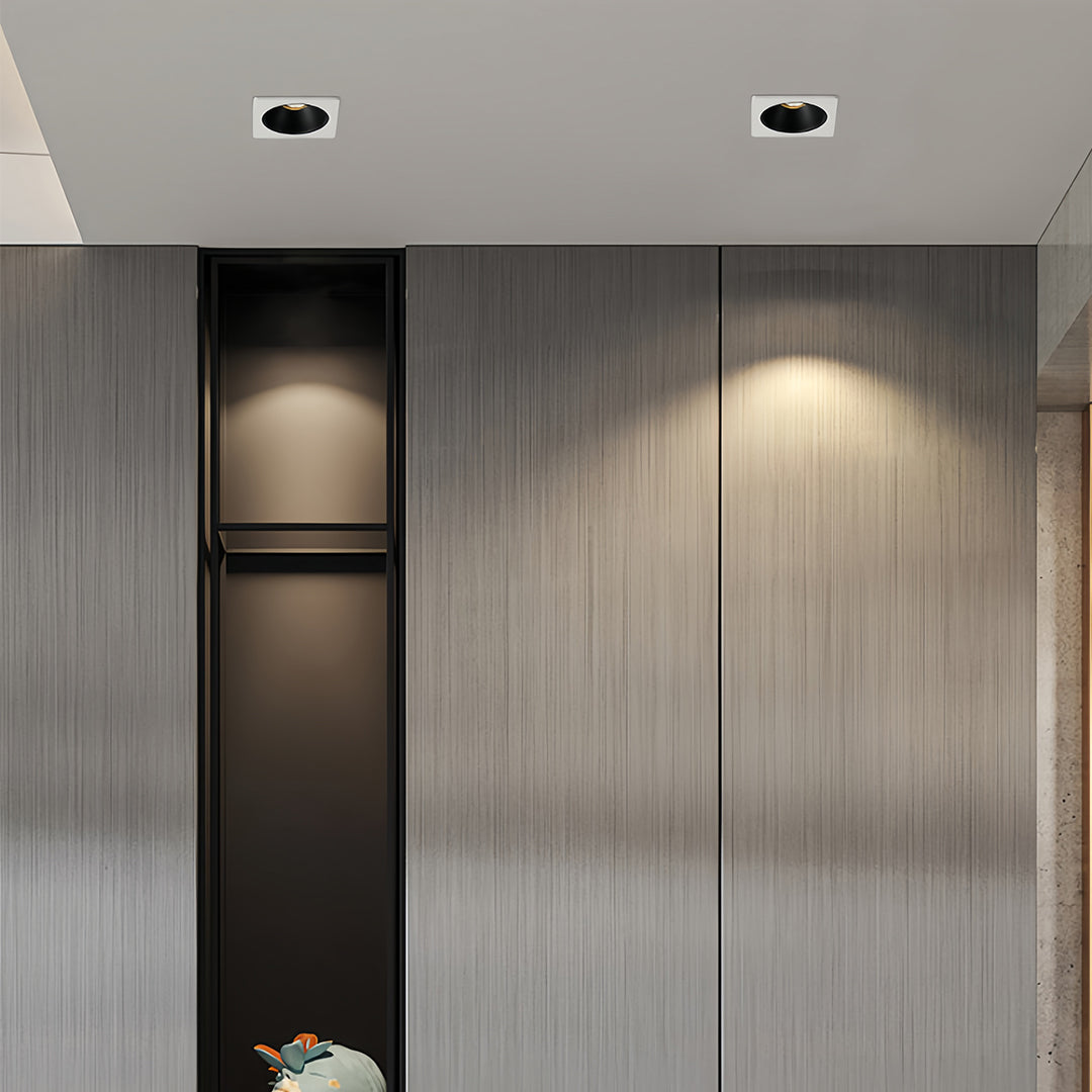 Triple square recessed downlight with black interior and white frame on a gray surface