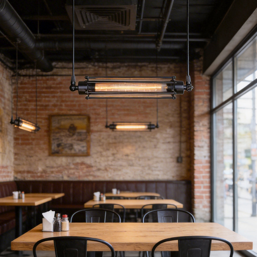 Tube pendant light installed above a wooden table in a modern industrial-style cafe.