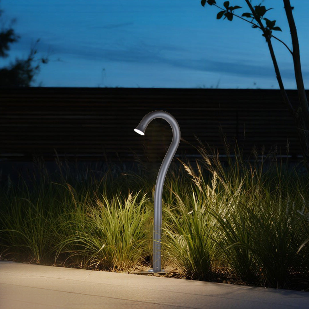 Dramatic twilight scene with curved pathway lights creating artistic illumination in natural setting
