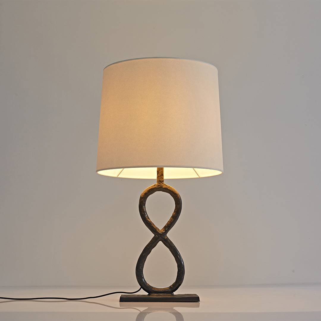 Twisted bronze metal table lamp with drum shade, simple and elegant home decor lighting.