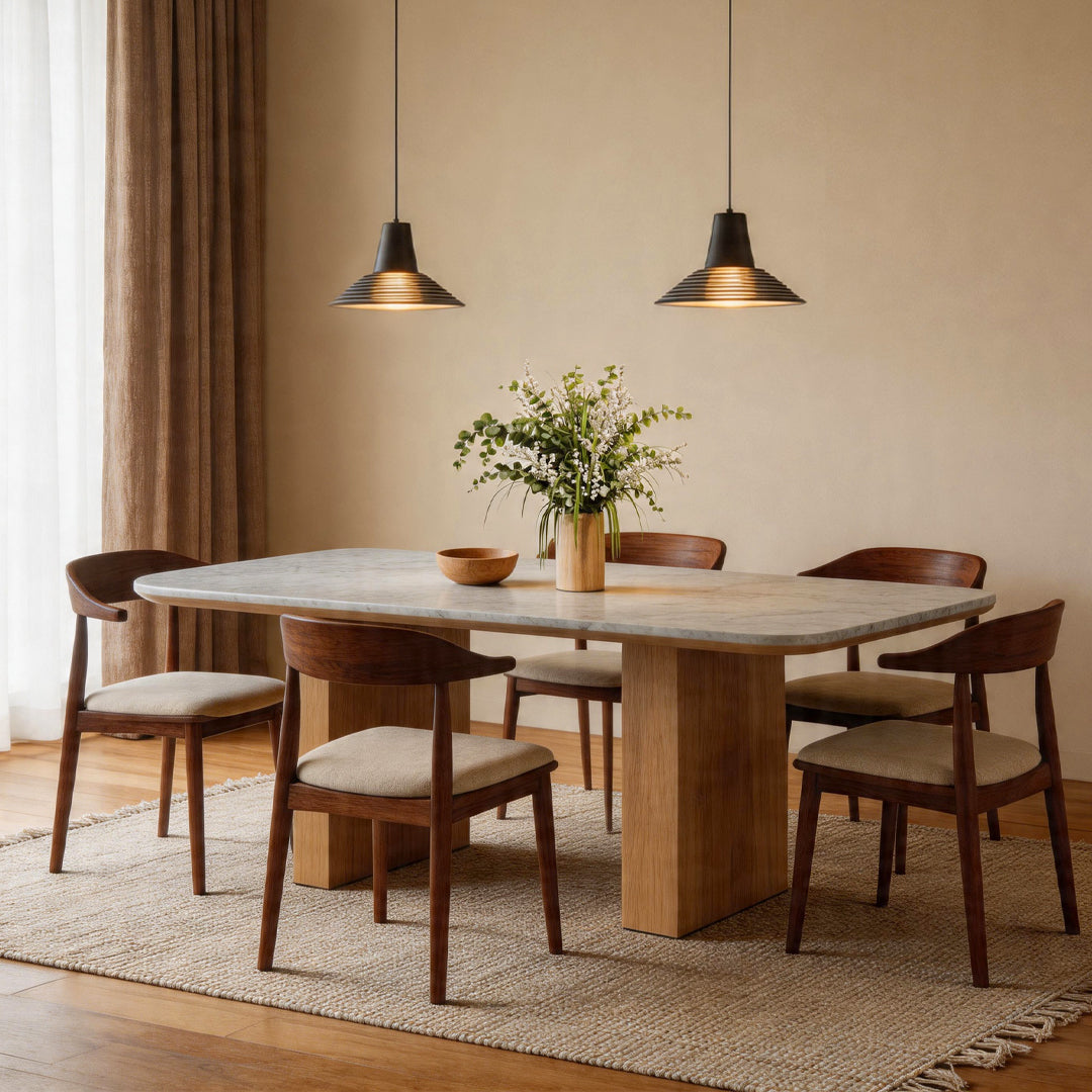Two glass cone pendant light fixtures hanging over a marble dining table and wooden chairs area