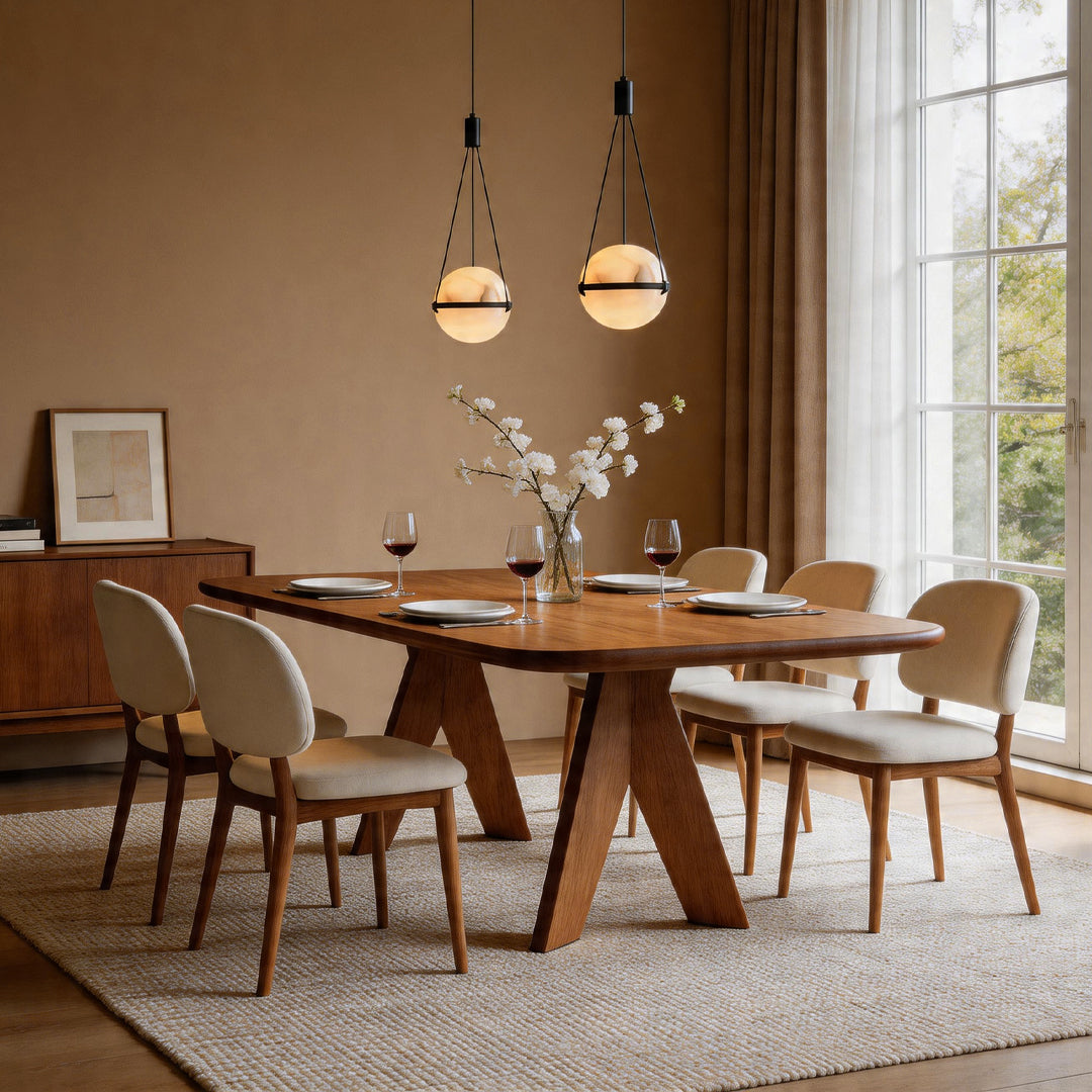 Two globe pendant light fixtures illuminating a wooden dining table in a warm beige room area.