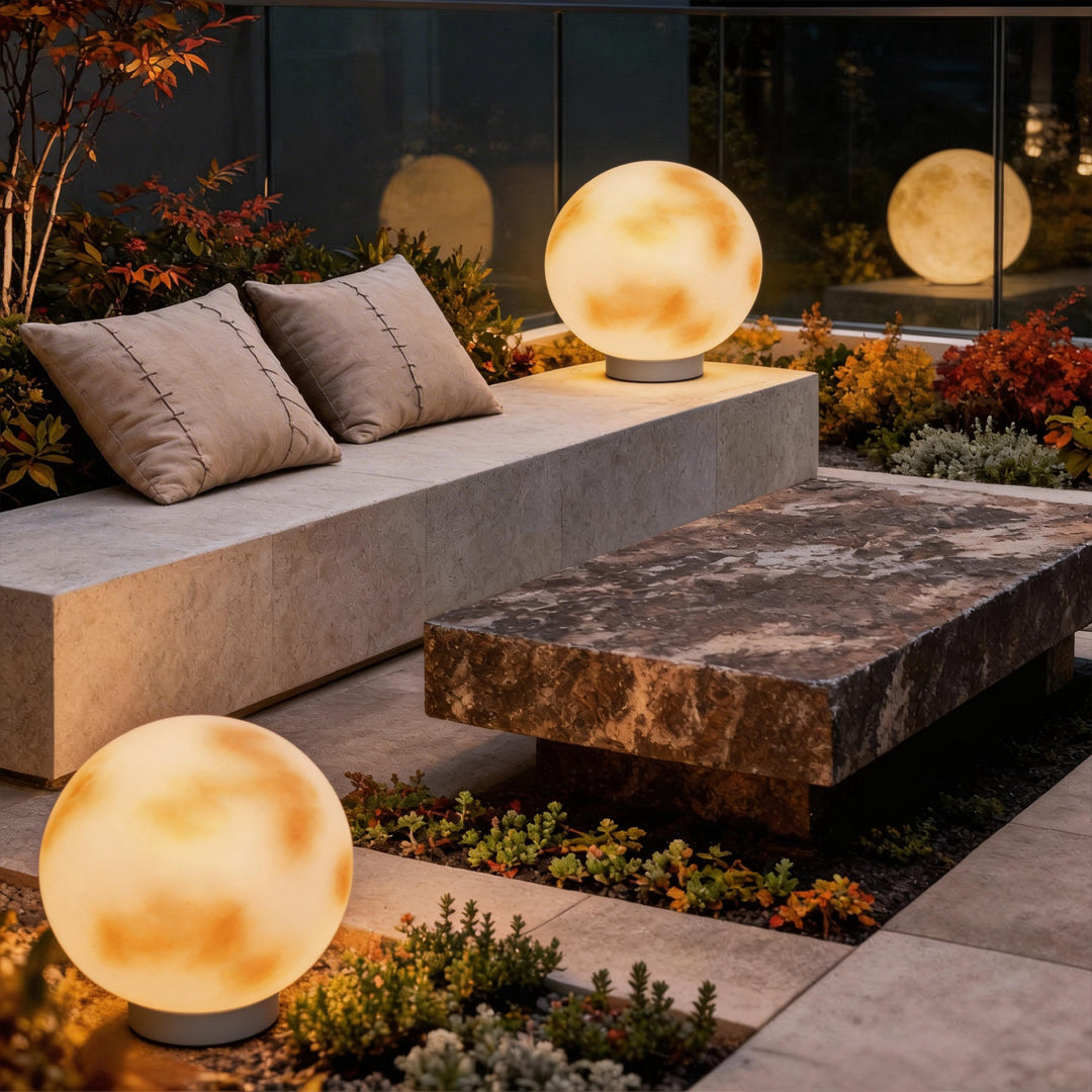 Two moon-shaped stone pillar lights illuminating a contemporary patio with stone seating area.