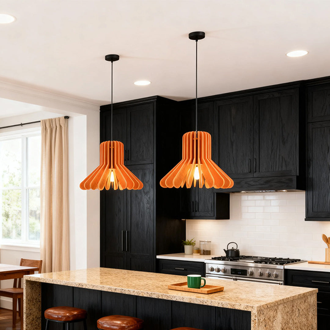 Two orange wood-slat tiny pendant lights illuminating a kitchen island with black cabinets 
