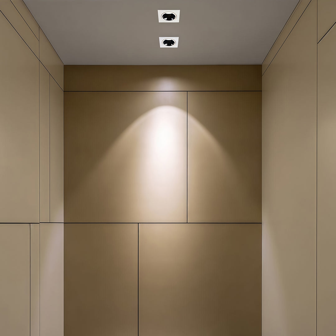 wo square recessed downlight fixtures creating a focused wall-wash effect on a beige paneled wall.