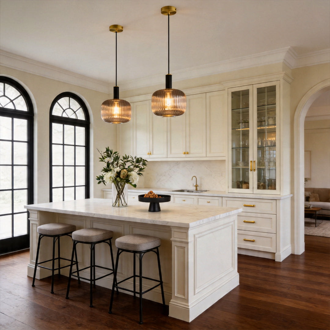 Two vintage glass pendant light fixtures illuminating a white marble kitchen island and stools.