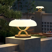 Modern hollow square pillar light with umbrella-style LED shade illuminating outdoor concrete pedestal in landscape setting