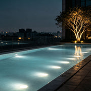 Underwater spot lights illuminating a modern swimming pool at night, creating a soft glow beneath the water surface.