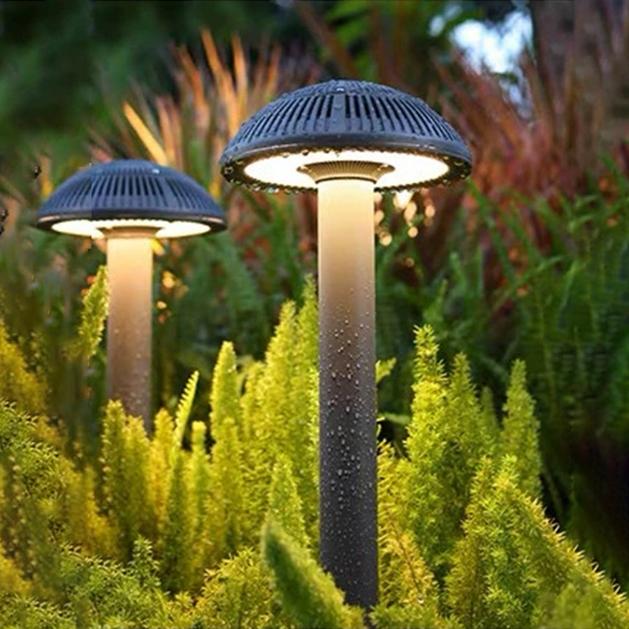 Multiple illuminated bollard lights creating uniform lighting along landscaped pathway with colorful plants