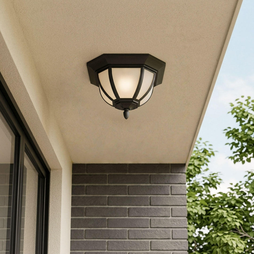 Unique flush mount lighting with a black geometric frame installed on a covered outdoor entry ceiling.