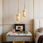 Unique gold pendant light hanging above a modern bedside table in a minimalist bedroom.