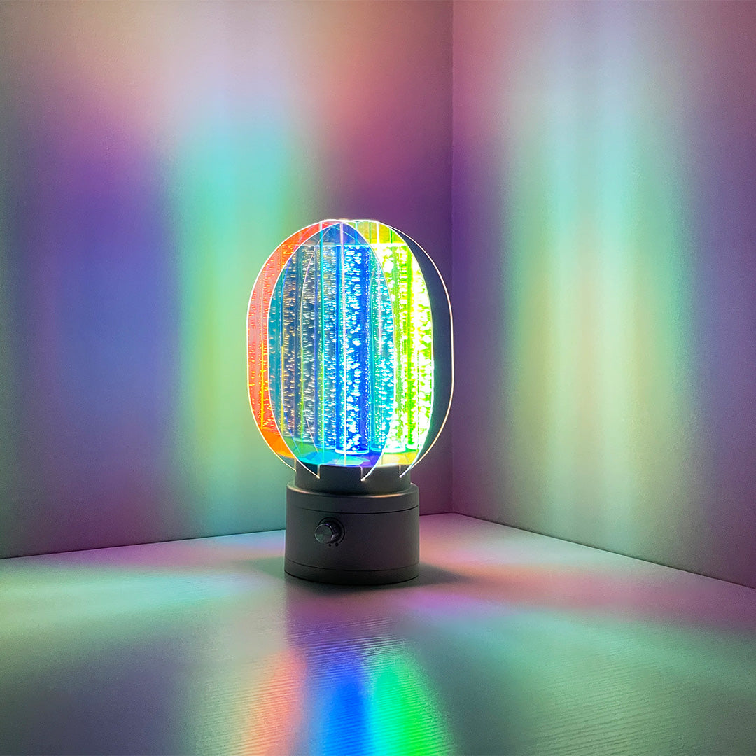 Unique colourful table lamp casting bright, saturated light onto a white wall, perfect as an accent piece for a modern, artistic room.