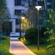 Unique street lighting fixture casting warm light along a pathway in an urban park.