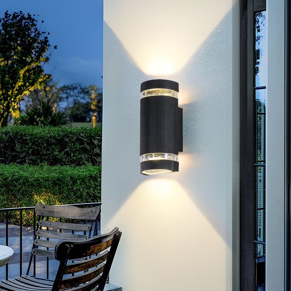 Up and down light wall sconce mounted beside a garden pathway, providing ambient outdoor lighting.