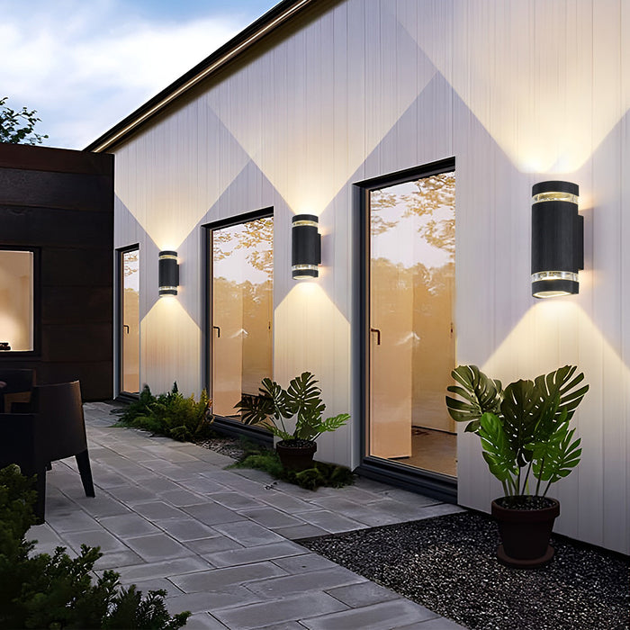 Up and down light wall sconce installed along a modern building exterior, casting warm illumination.