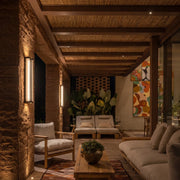 Up and down light wall sconce mounted on a textured patio column, casting warm vertical light in a covered outdoor lounge.