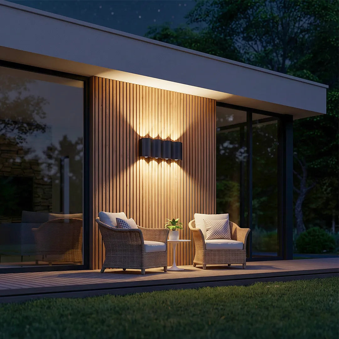 Up and down outdoor wall lights installed on a wood-clad modern patio wall beside lounge seating.