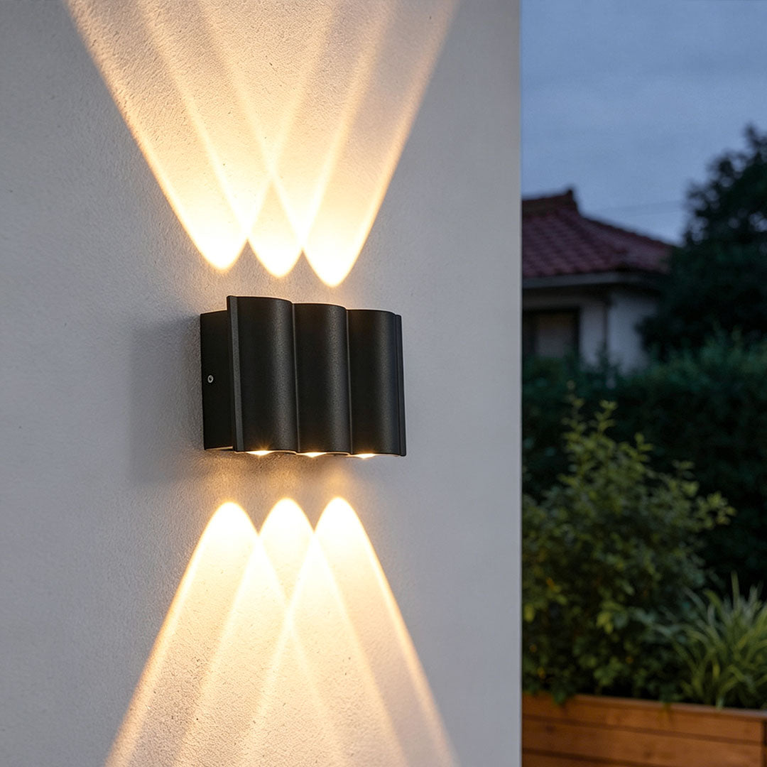 Up and down outdoor wall lights mounted on a white exterior wall, casting warm bidirectional beams.