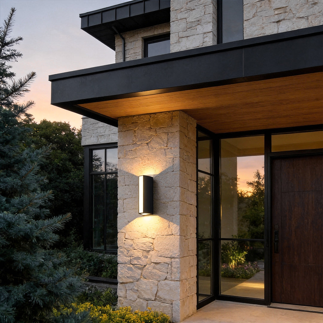 Up down cylinder sconce mounted on a modern home exterior, creating warm vertical light beams that accent stone and wood architecture.