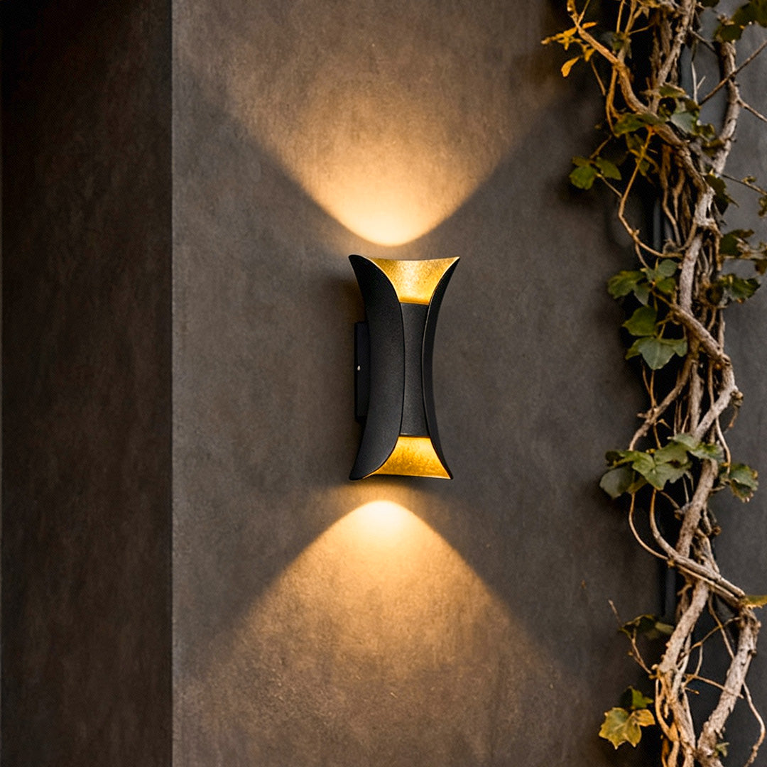 Close-up of black and gold up down lighting wall lights highlighting texture on exterior wall with ivy decor.