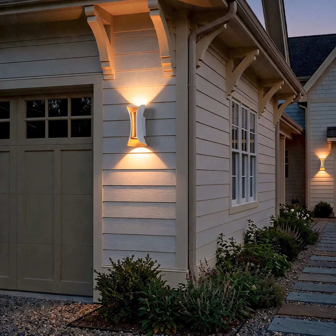Up down lighting wall lights installed along a house exterior, illuminating the siding and walkway with warm ambient light.