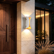 Up down lighting wall lights mounted on a modern exterior column, creating a warm glow beside a wooden front door.