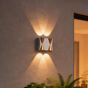Up down lighting wall lights with a modern gold and black design, mounted beside a glass door.