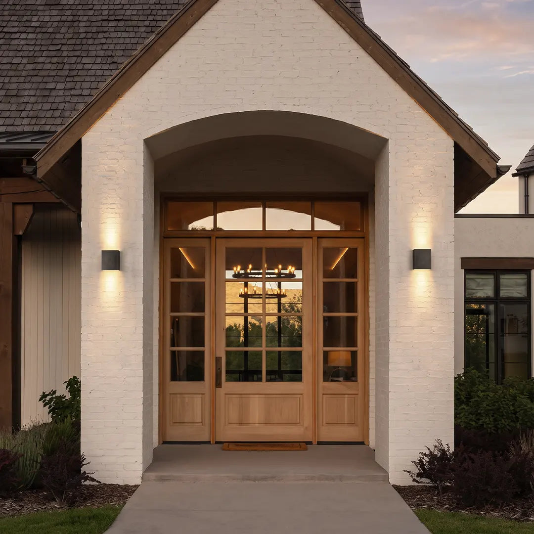 Up down lighting wall lights mounted beside a front door on a white brick exterior with soft architectural wall wash.