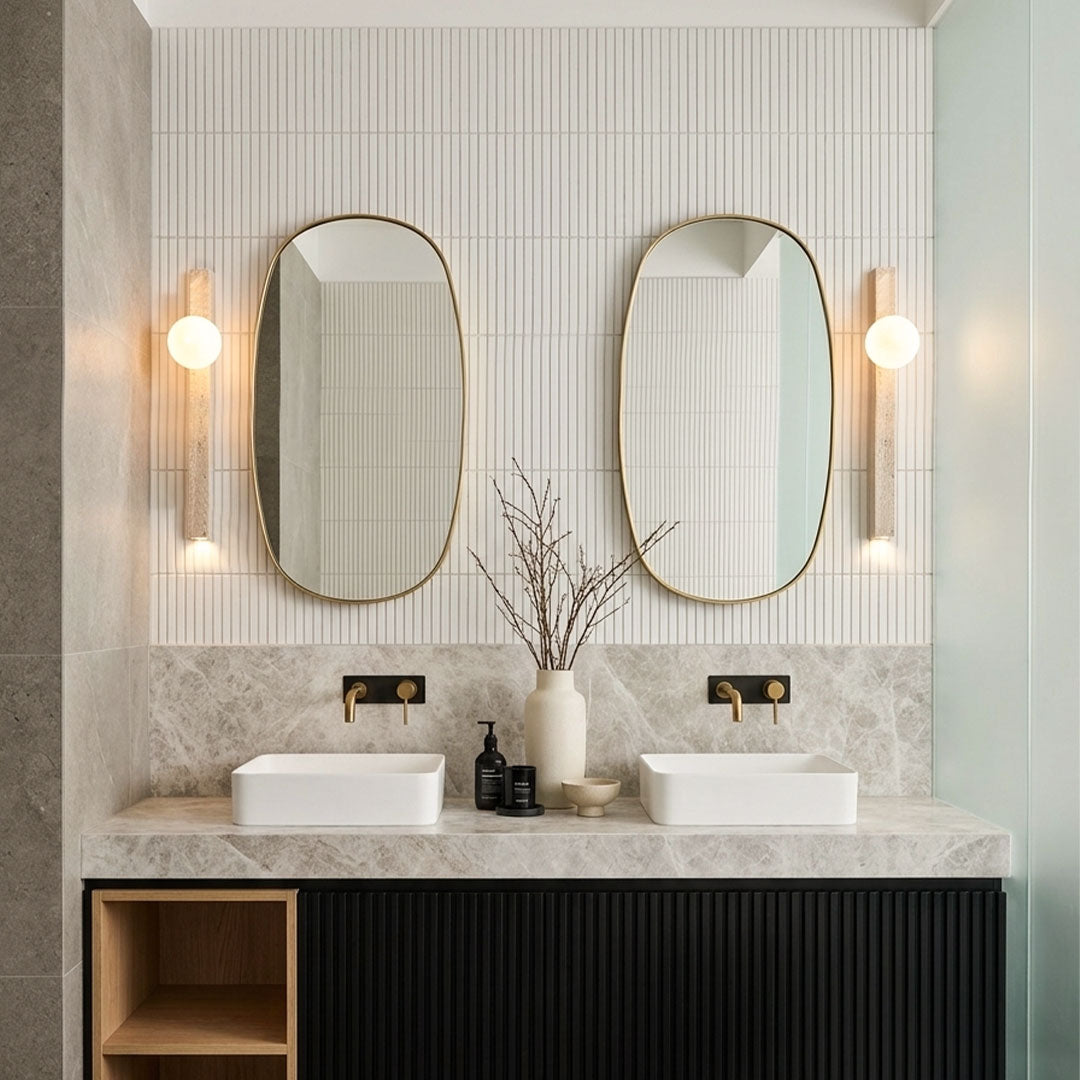 Up down lighting wall sconce mounted beside bathroom mirrors with warm globe illumination.