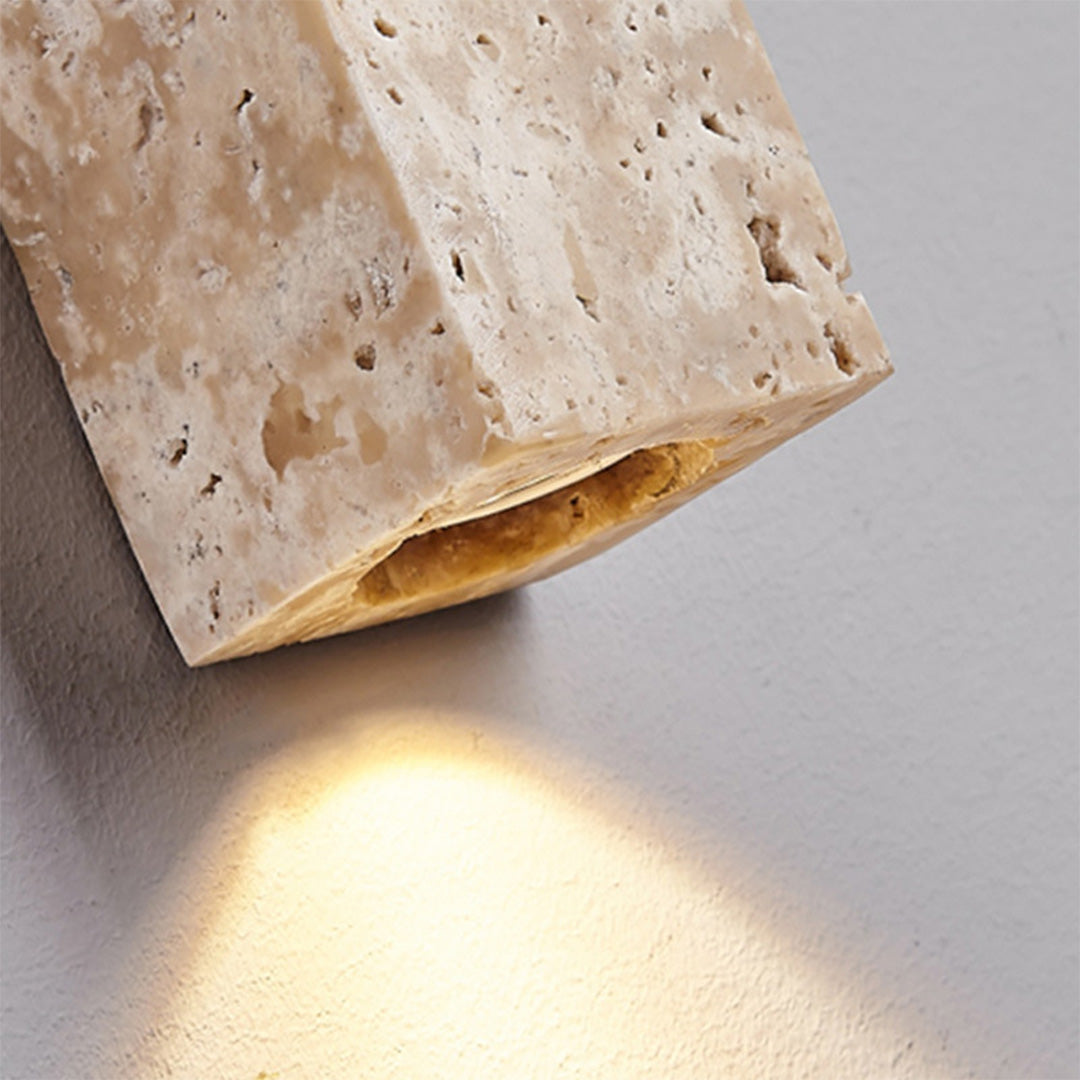 Close-up of up down lighting wall sconce showing the stone texture and downward light beam.