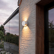 Up and down wall lights illuminating a modern house facade with warm directional glow.