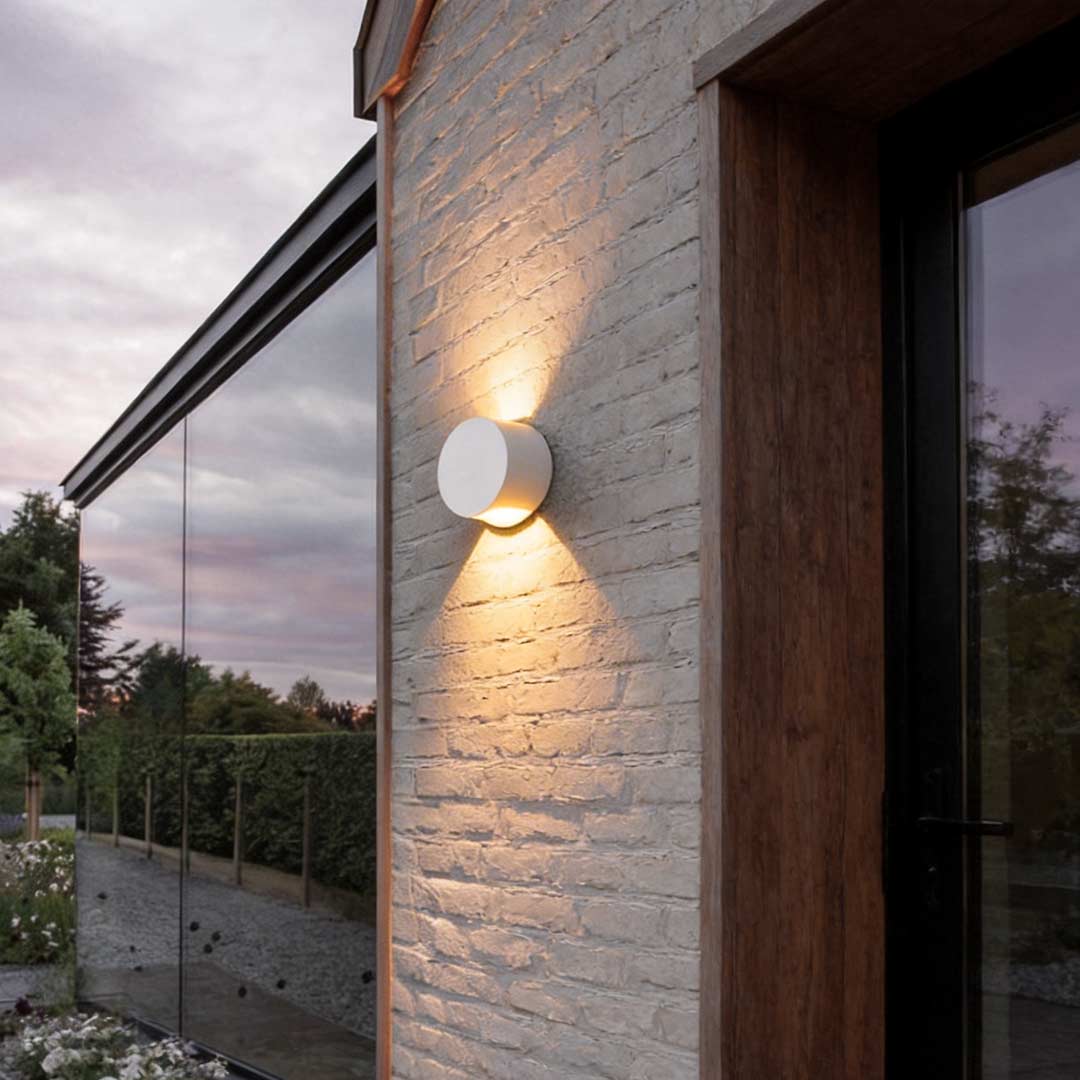 Up and down wall lights illuminating a modern house facade with warm directional glow.