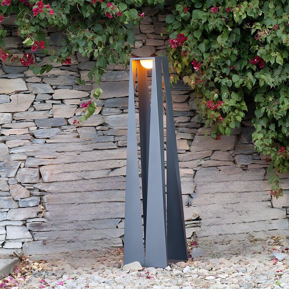 Outdoor landscape lighting flood lights providing upward illumination along garden pathway with natural stone and plant backdrop