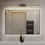 Modern bathroom mirror illuminated by slim black vanity LED lights for mirror, creating soft and even lighting above a rectangular wall mirror.