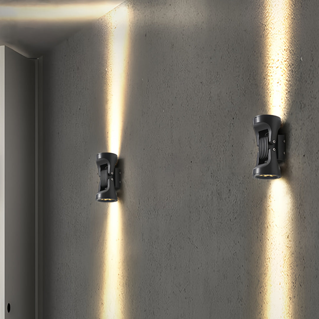 Vertical two light wall sconce casting dramatic up and down beams on a textured wall surface.