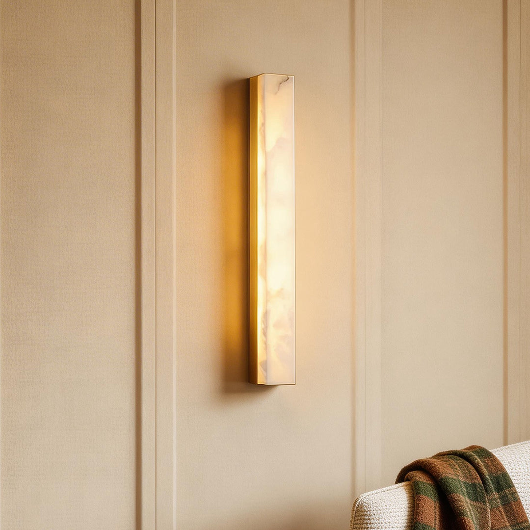 Modern copper sconce indoor with a vertical alabaster stone front glowing on luxury beige wall.