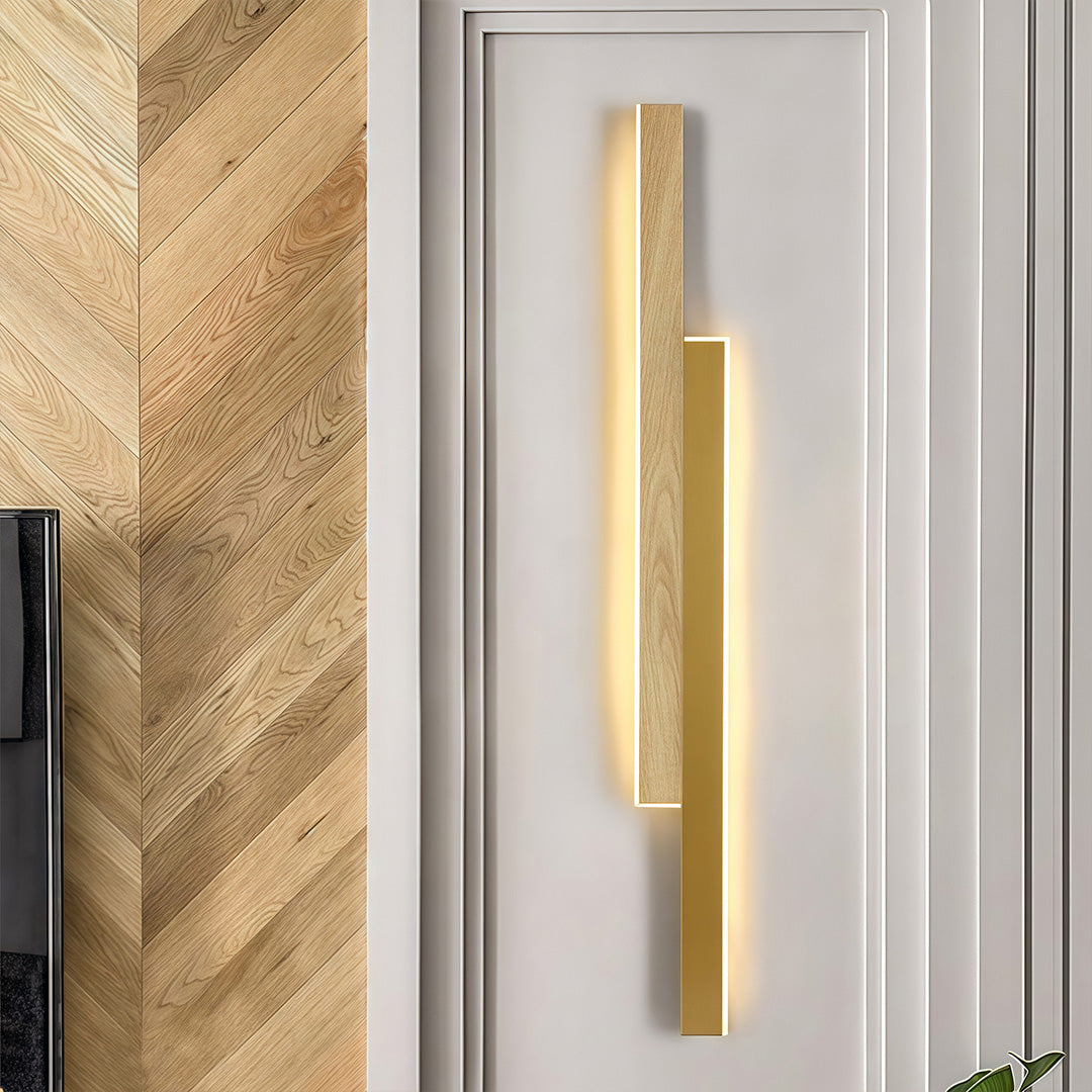 Vertical linear led wall light combining light wood grain and a sleek gold metal strip, mounted on a white door frame.