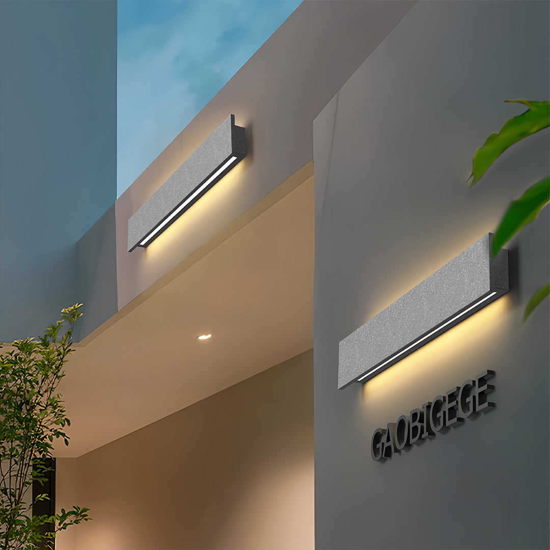 Sleek vertical modern outdoor wall sconces installed on a minimalist exterior façade with warm light.