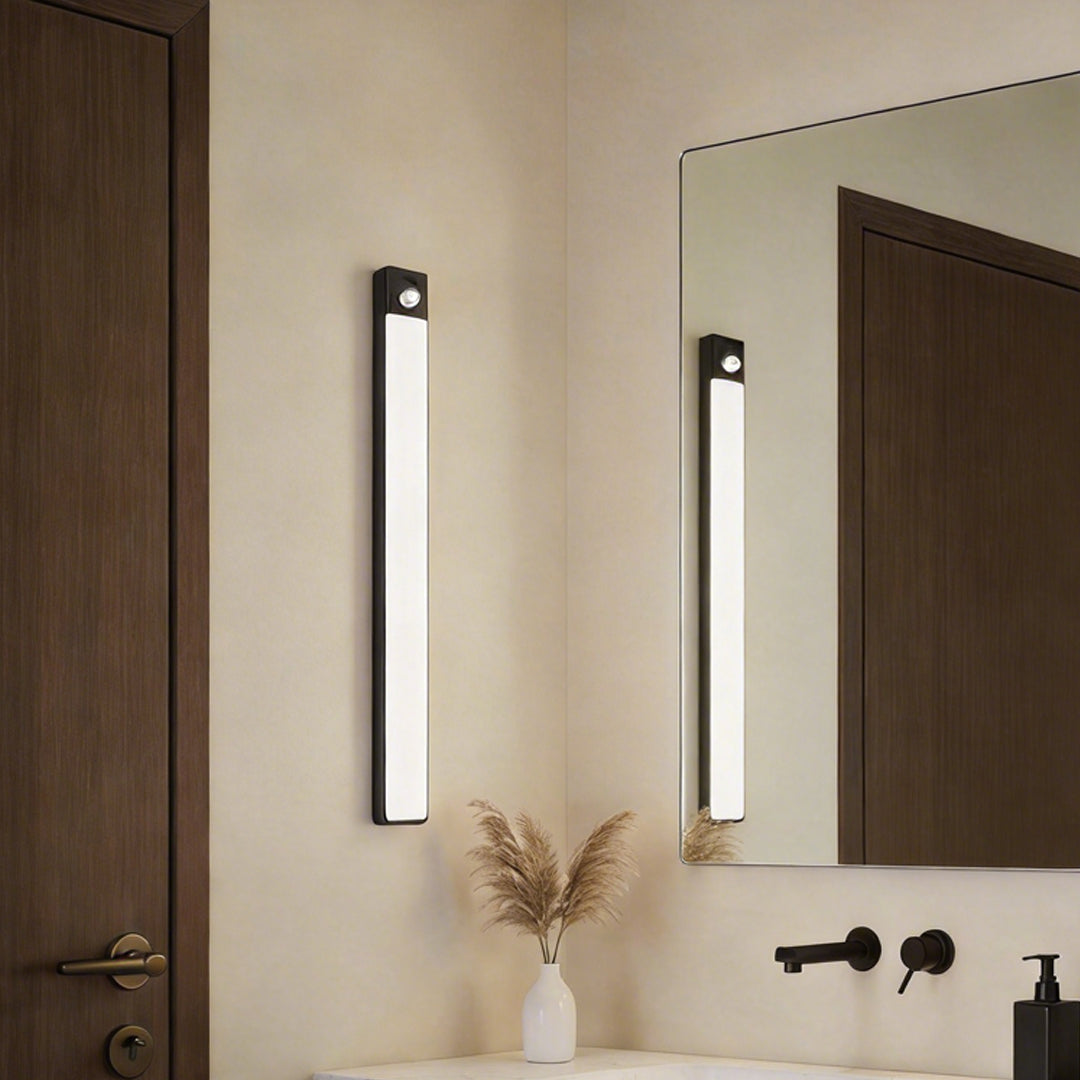 Vertical under cabinet sensor light installed next to a mirror in a modern bathroom setting ok.