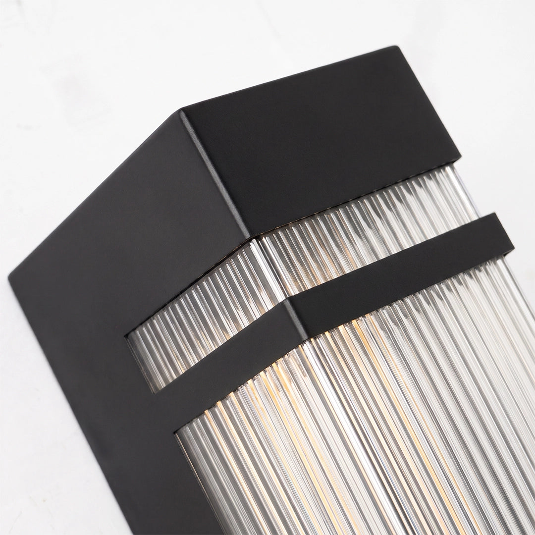Close-up of vertical wall lighting with a black rectangular frame and clear ribbed diffuser.