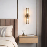 Vertical wall sconce lighting with a sleek gold design, illuminating a modern bedroom nightstand.