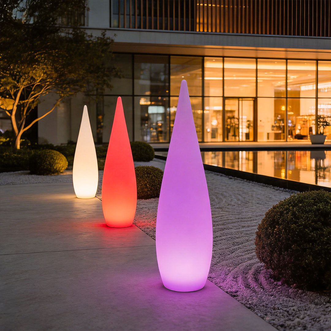 Vibrant modern teardrop outdoor light glowing with red and purple colors in a garden at night.