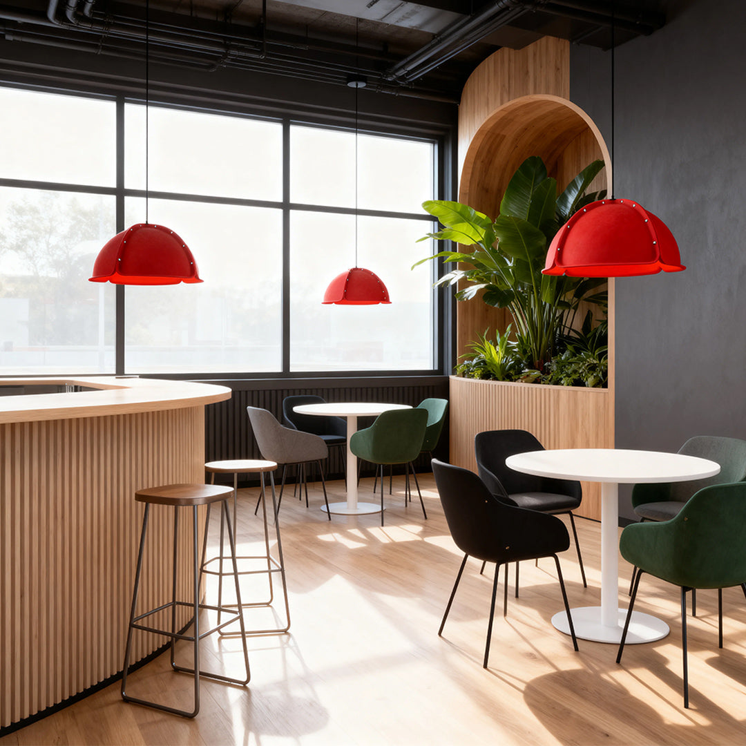 Three vibrant red colored pendant light fixtures hanging over a bar and seating area in a modern cafe space.