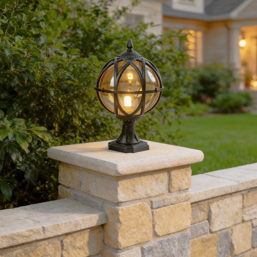 Vintage black globe pillar light on stone wall pillars with a suburban luxury home background.