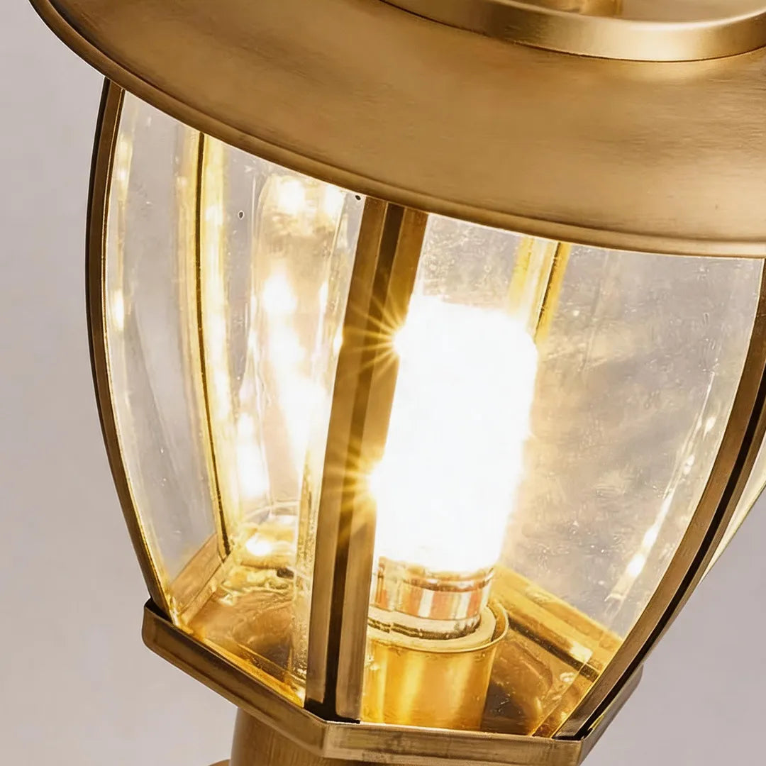 Vintage brass outdoor lantern with clear glass panels and warm bulb detail