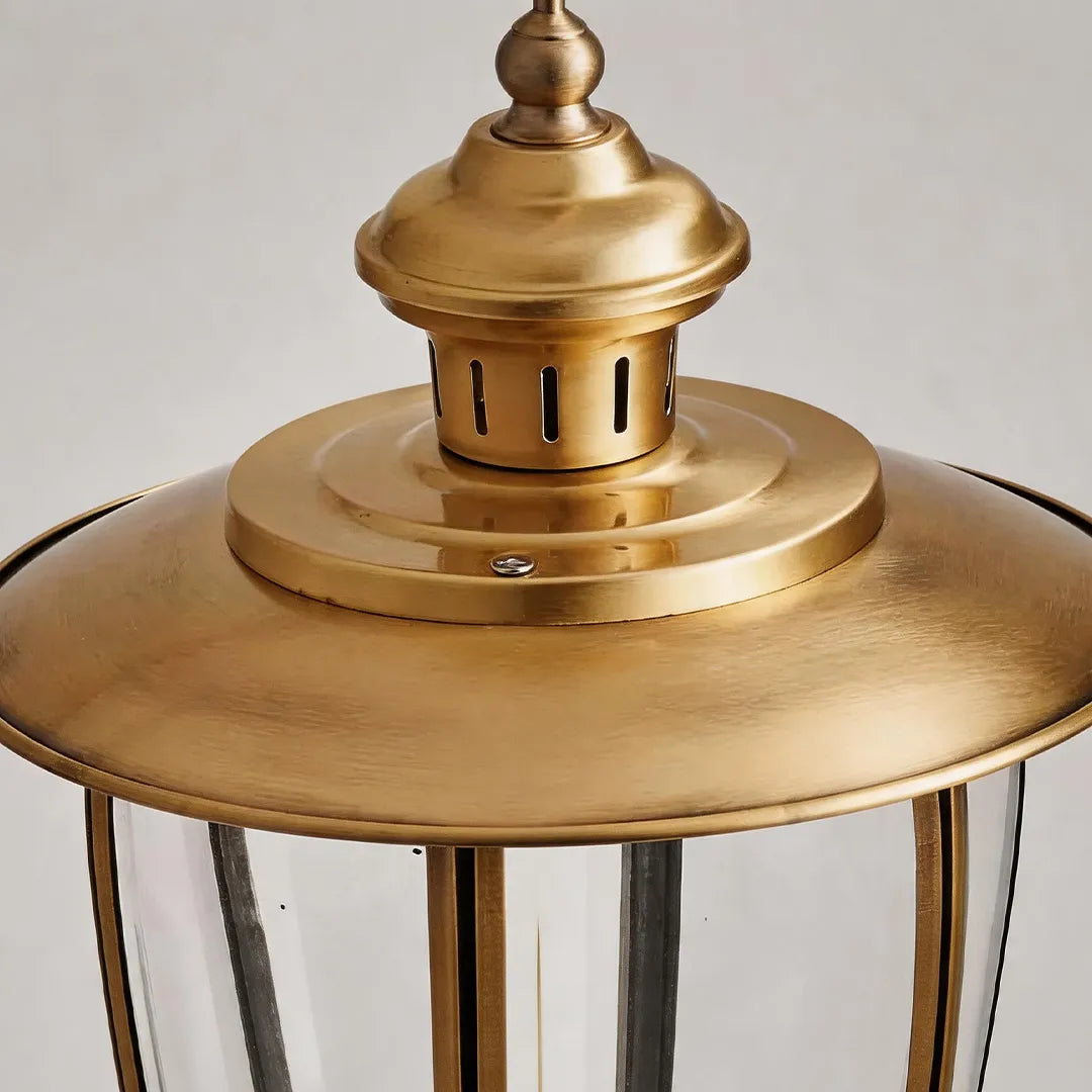 Vintage brass outdoor lantern with decorative metal top and classic finial detail